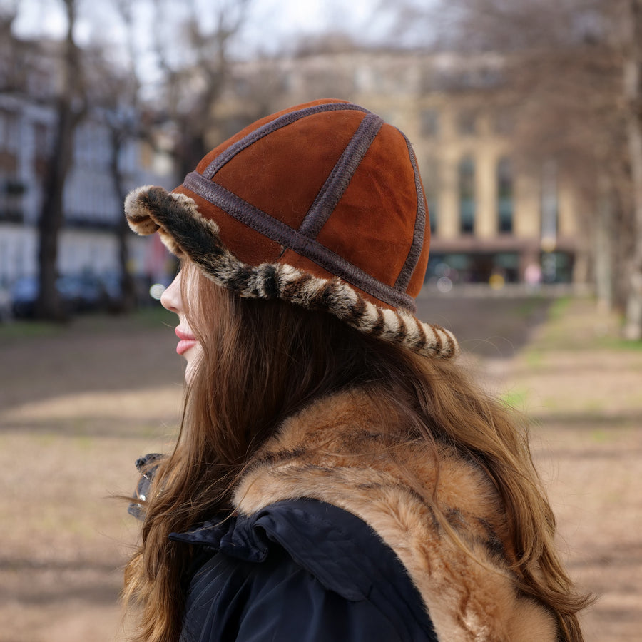 Person wearing a brown hat with fur trim in an outdoor setting