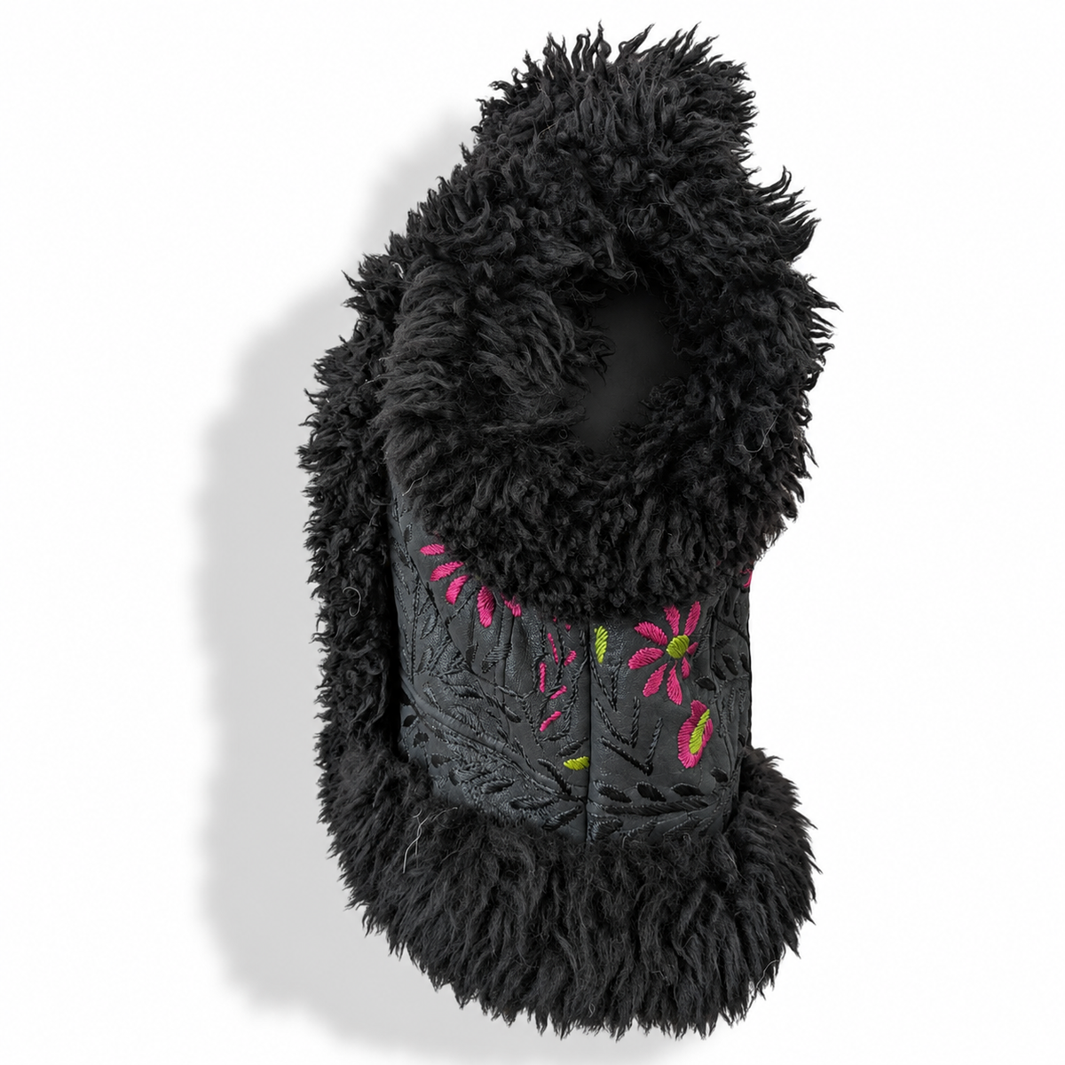 Close-up front view of a black shaggy faux-fur vest collar with a central embroidered panel featuring pink and green floral patterns, against a white background.
