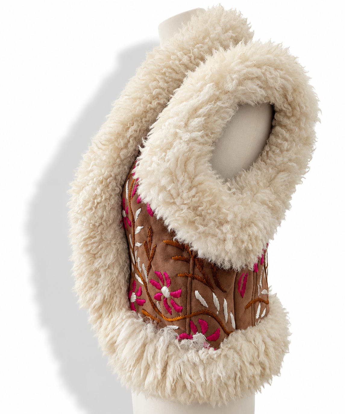 Side view of a vest with a cream faux-fur collar and trim, featuring a brown embroidered panel with pink and white floral patterns, displayed on a mannequin torso against a white background.