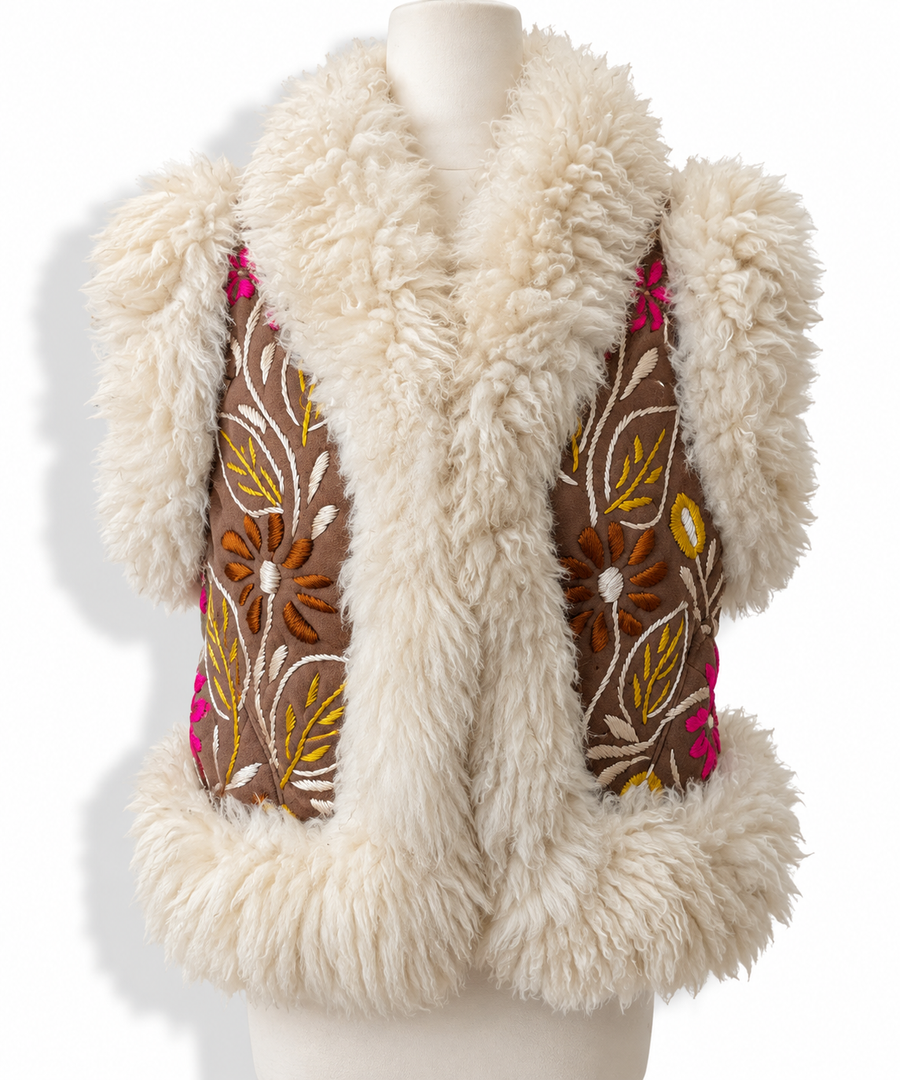A cream-colored shearling vest with brown embroidered panels featuring floral and leaf patterns in yellow, orange, and pink, displayed on a mannequin torso against a white background.