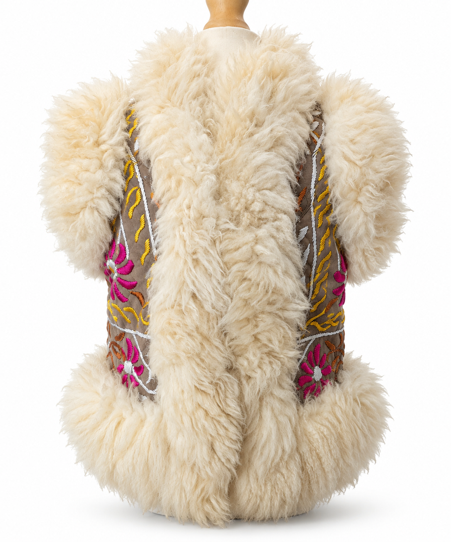 A cream-colored sheepskin vest with colorful embroidered floral details on the sides, displayed on a mannequin against a white background.