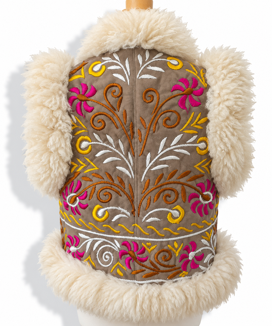 Back view of a brown shearling vest with cream faux-fur trim, featuring vibrant pink, orange, yellow, and white floral and vine embroidery, displayed on a mannequin torso against a white background.