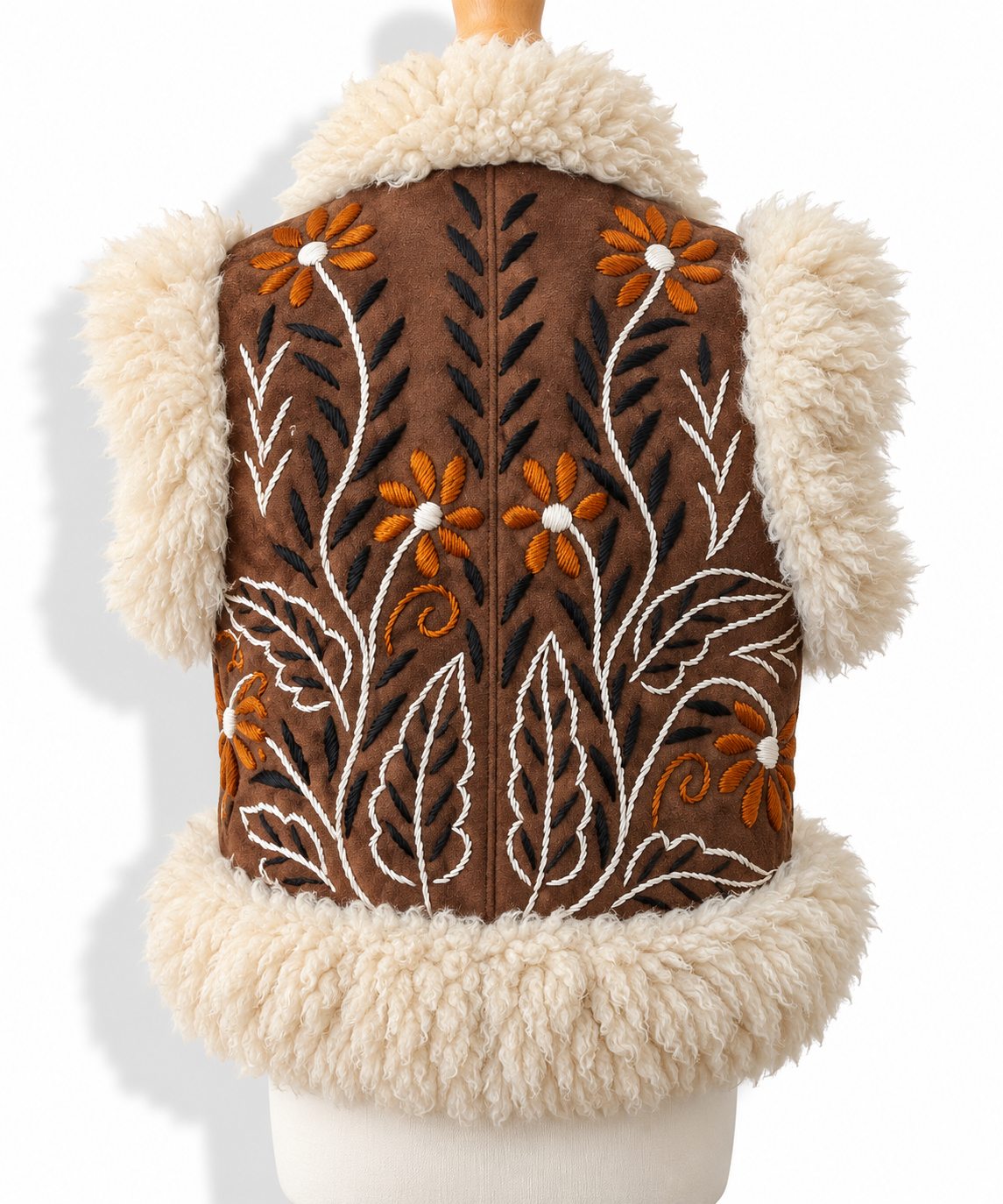 A brown suede vest with cream and white shearling trim, featuring embroidered floral and leaf patterns in orange, white, and black.