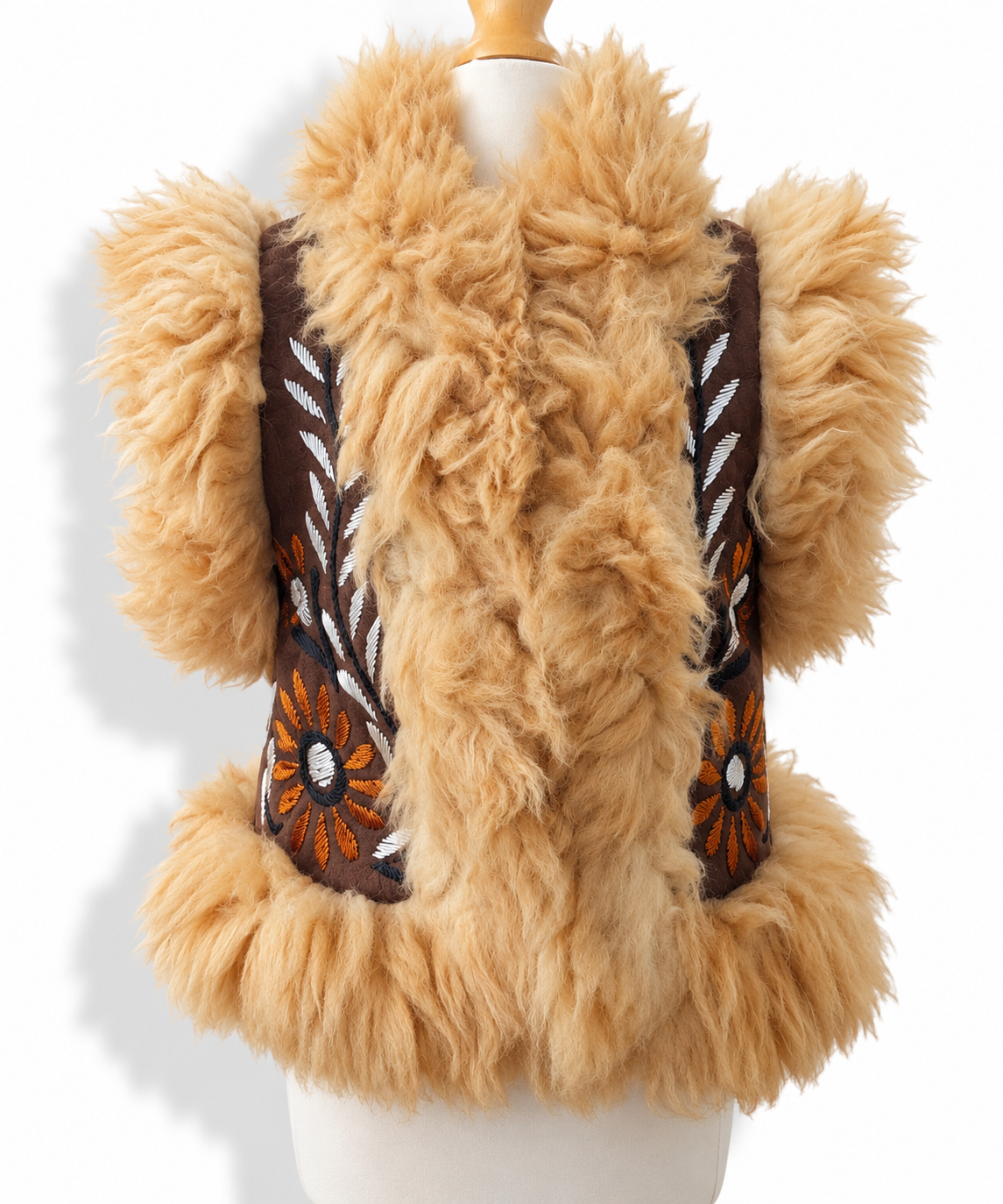 A tan faux fur vest with brown embroidered panels featuring orange and white floral details, displayed on a white mannequin torso against a white background.