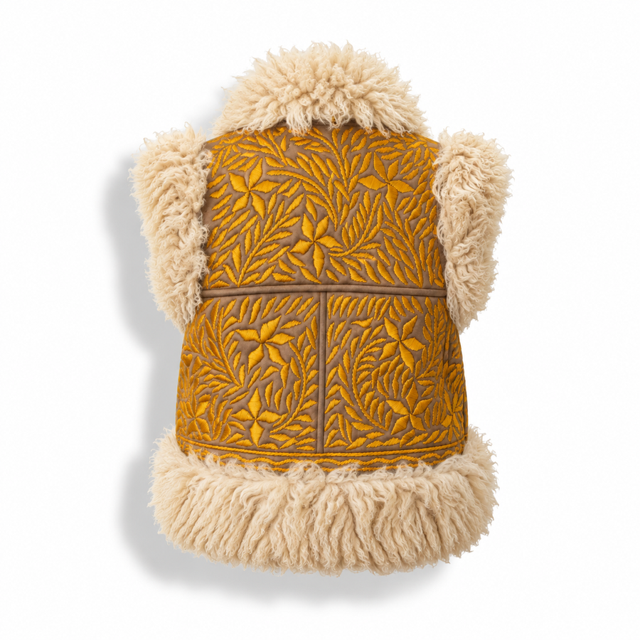 Back view of a vest with tooled brown and mustard leather body featuring a leaf pattern, and fluffy cream faux-fur trim on the hood, collar, and hem.