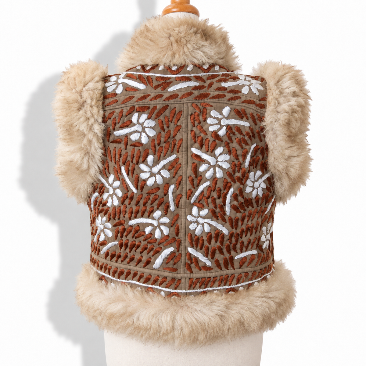 A brown vest with white floral embroidery and beige faux fur trim, displayed on a cream mannequin torso against a white background.