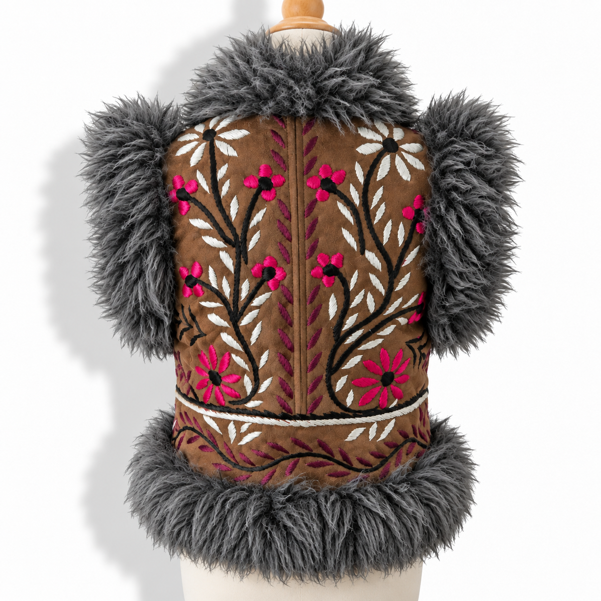 A brown suede vest with dark gray faux fur trim on the shoulders and hem, featuring pink and white floral embroidery on the front, displayed on a mannequin torso.
