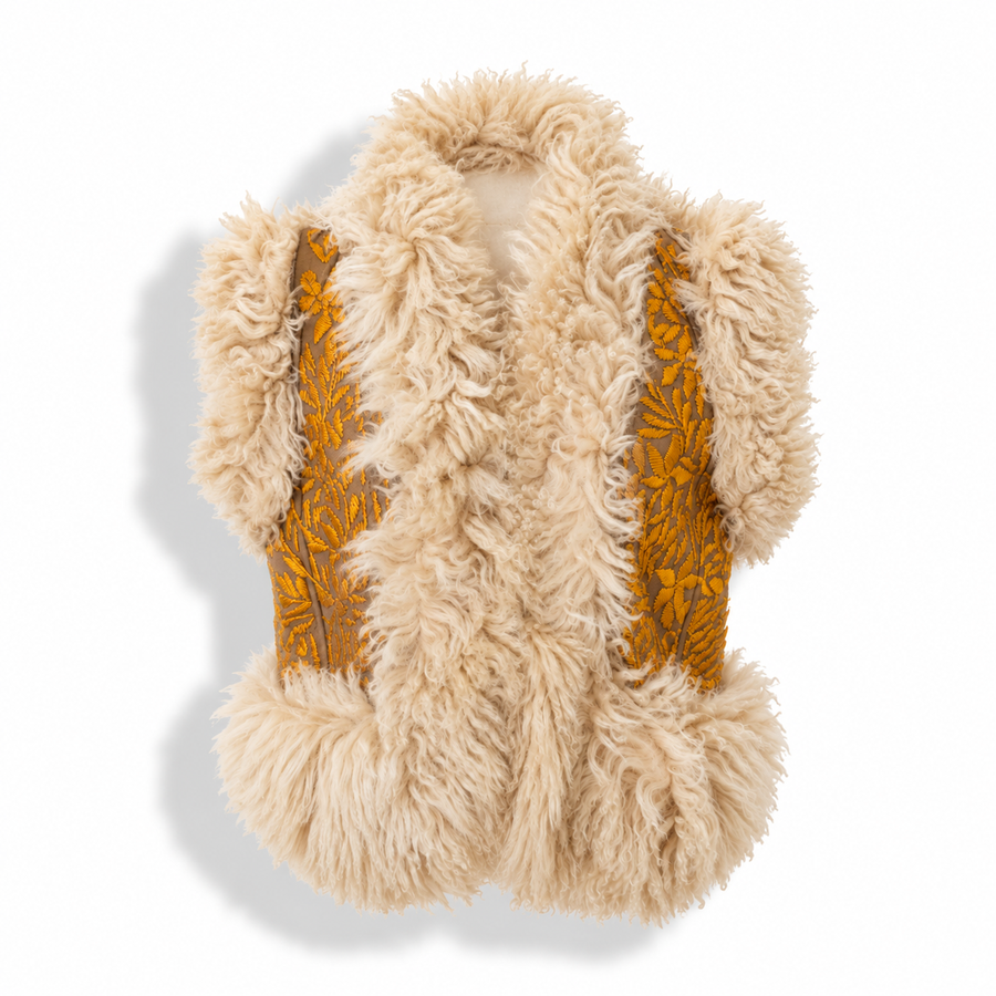 A sleeveless beige faux fur vest with mustard yellow embroidered leaf patterns on the sides, shown against a white background with a soft shadow.