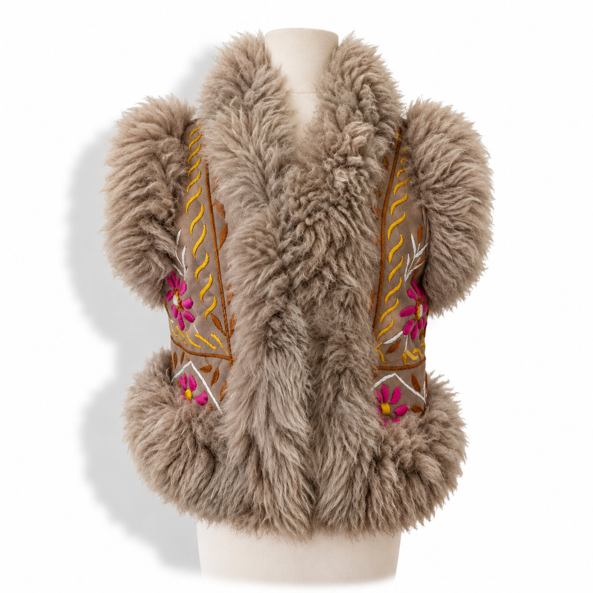 A shaggy taupe faux fur vest with pom-pom sleeves and embroidered side panels featuring pink flowers and gold details, displayed on a mannequin torso against a white background.